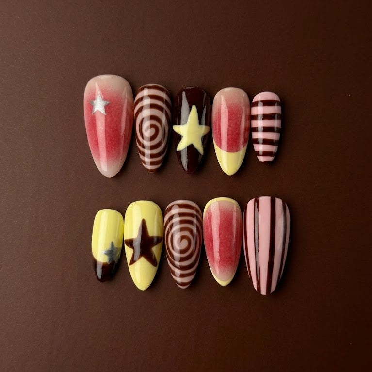 Y2K press-on nails with star accents, retro swirls, striped nail art, red aura gradients, brown details, and yellow French tips.
