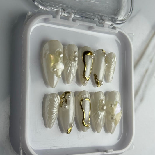 Set of decorative nails with gold accents in a clear container on a white background