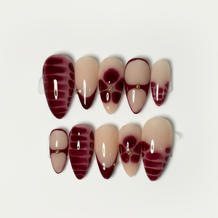 Set of press-on nails with a maroon and beige design on a white background