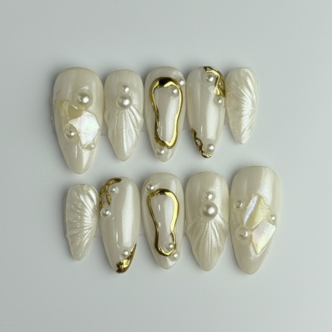 Set of decorative nails with gold accents and pearls on a gray background