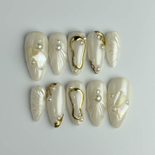 Set of decorative nails with gold accents and pearls on a gray background